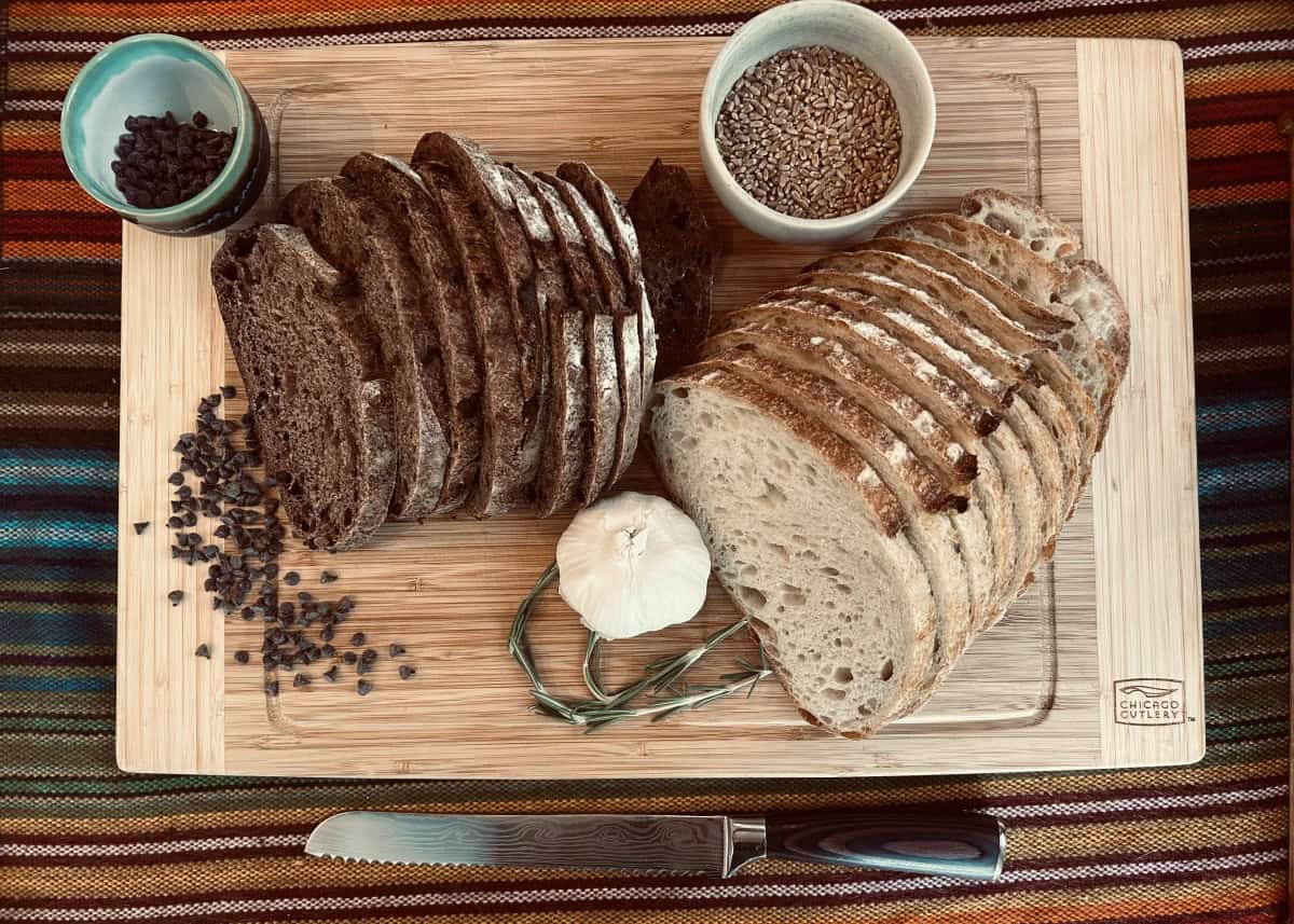 Dark and light sliced bread with ingredients: a head of garlic, herbs, spices, and chocolate chips