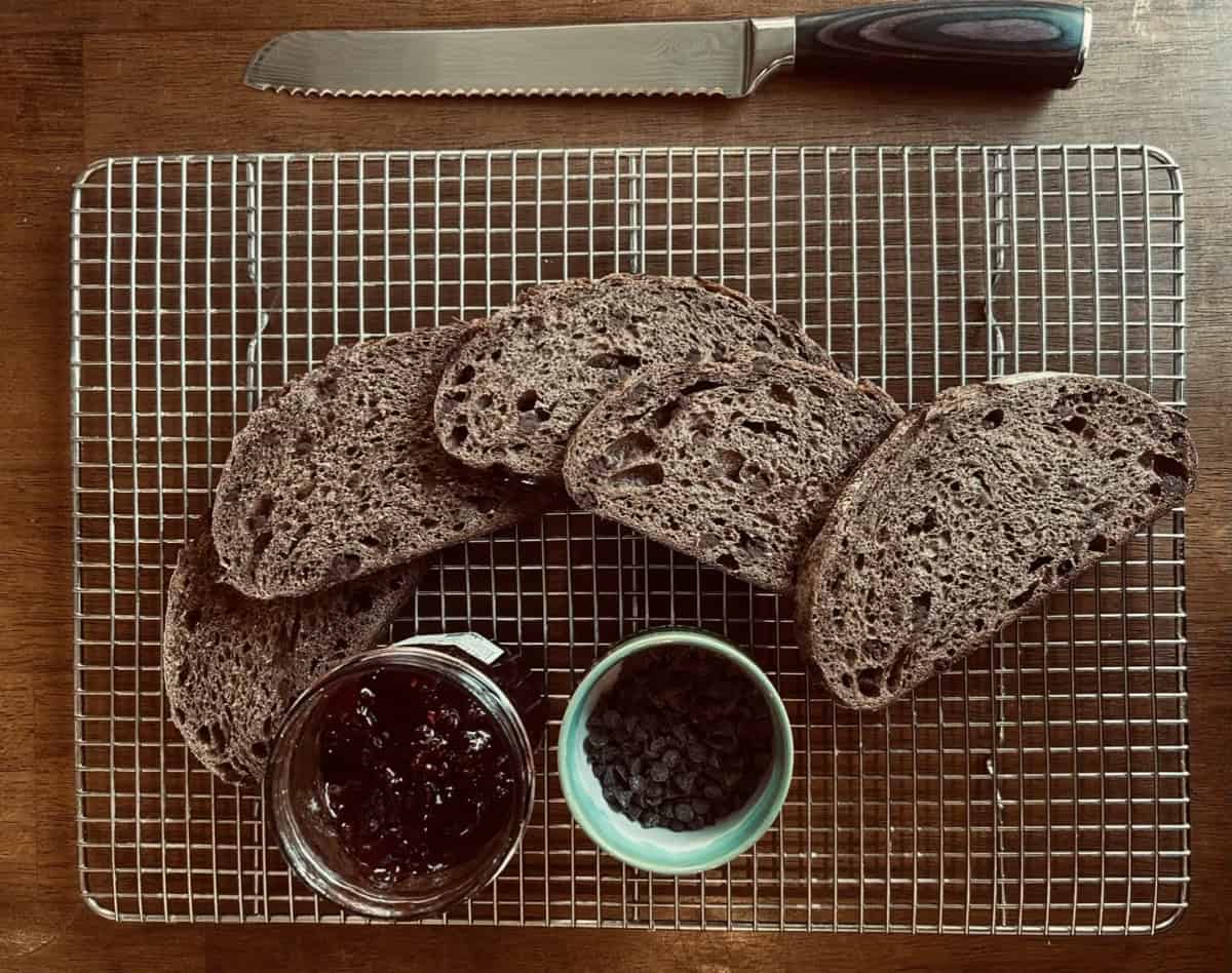 Sliced chocolate sourdough with a bowl of chocolate chips and a jar of jam