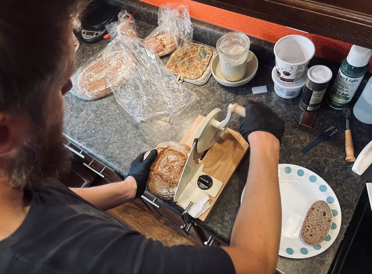 Erin slicing bread with an array of ingredients in the background